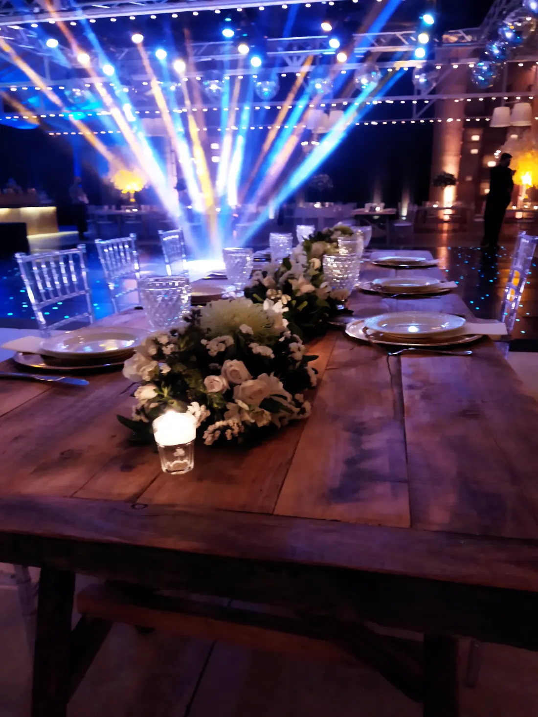 Centro de flores blancas y velas sobre una mesa de madera